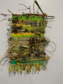 A beautiful woven wall hanging adorned with plants and twigs.
